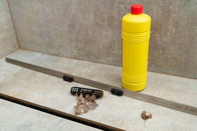 iStock-1429696283 hoe een afvoer te ontstoppen Vloeibare reiniger in een gele fles voor het reinigen van rioolafvoeren