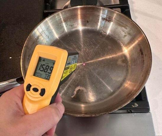 Az a személy, aki ThermoWorks IR pisztolyt használ a rozsdamentes acél edény felületi hőmérsékletének mérésére