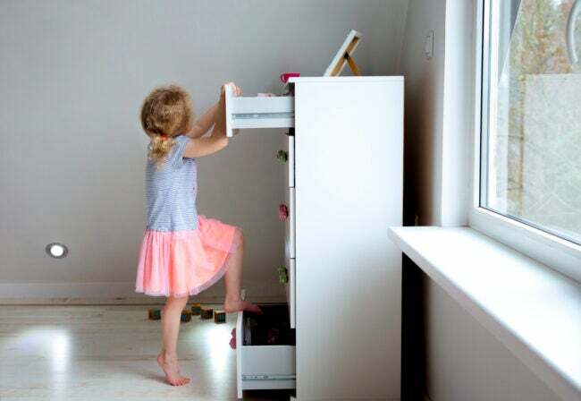 كيفية تثبيت الأثاث على الحائط. طفل يتسلق على خزانة الملابس غير مستقر