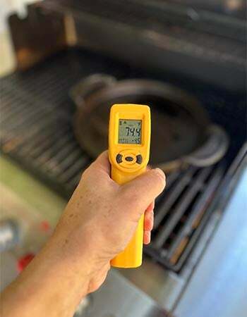 Persoon die de binnentemperatuur van de grill meet met een geel Thermoworks IR-pistool