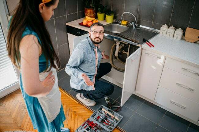 ชายและหญิงกำลังแก้ไขปัญหาอ่างล้างจานในครัว