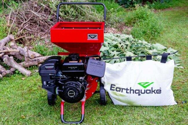 Triturador de madeira Red Earthquake K33 na grama ao lado de um saco de lascas de madeira