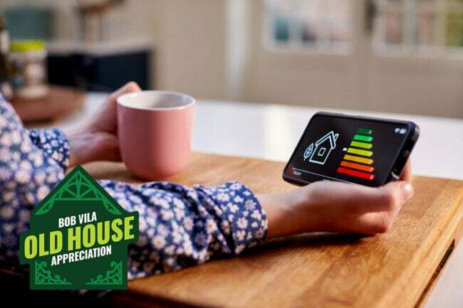 energetsko učinkovita stara hiša oseba, ki drži zaslon za energetski pregled