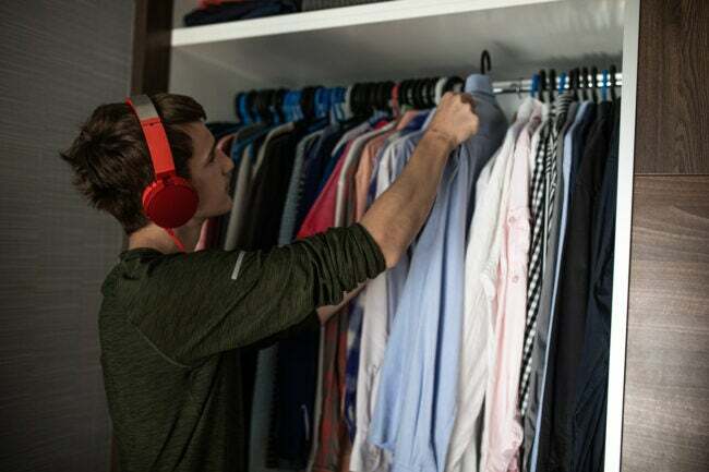 Teenager organisiert seinen Kleiderschrank und hängt Kleidung auf einen Kleiderbügel