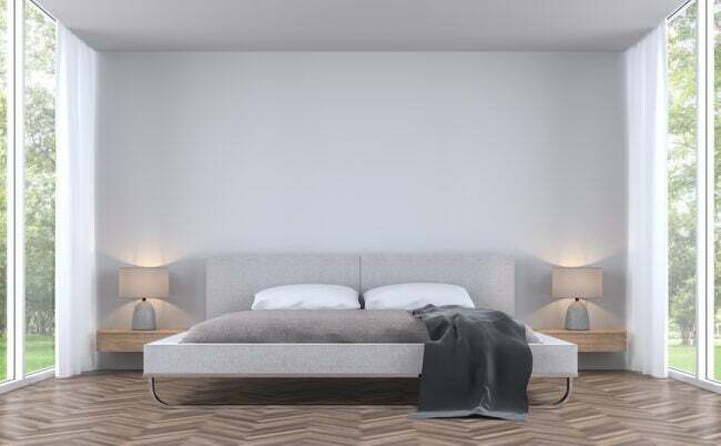 Soverom i moderne stil med hageutsikt 3d-gjengivelsesbilde. Det er hvit vegg og tregulv ferdig med stoff seng. Det er store vinduer med utsikt over den omkringliggende hagen og naturen