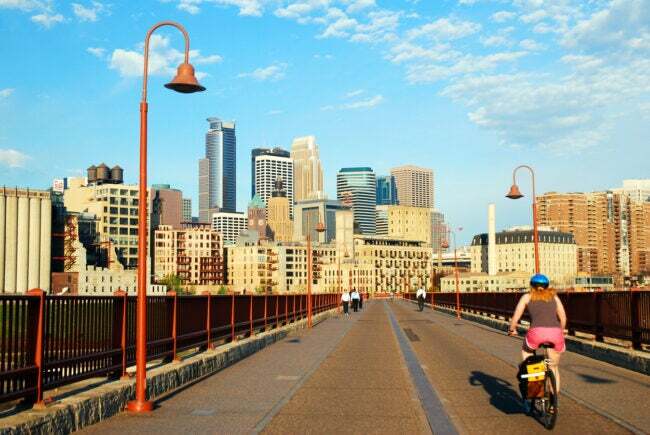 Un cycliste pédale sur le pont Stone Arch, en direction de Downton Minneapolis, Minnesota