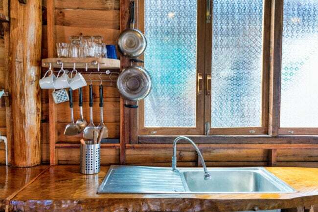 Rustikálna, drevom obložená kuchyňa s nerezovým drezom a oknami z matného skla