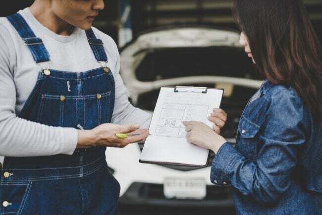 Mecánico y cliente revisando una factura de mantenimiento de reparación de automóviles