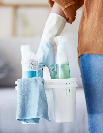 Особа држи кутију производа за чишћење и плаву крпу.