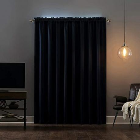 Tirai gelap menutupi jendela di ruang tamu yang remang-remang
