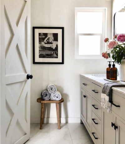 Een zicht op een lichte binnenbadkamer met zichtbare wastafel en open deur en lichtgrijze muren