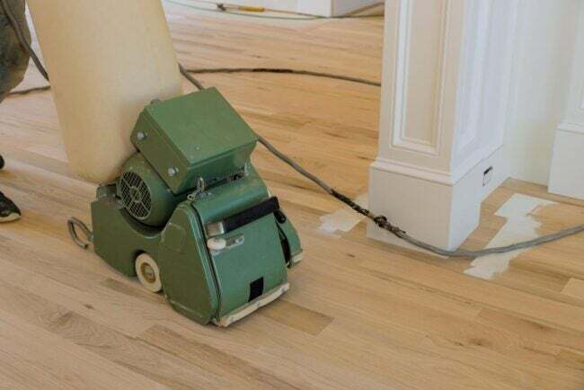 Žmogus stumdo žalią grindų šlifuoklį.