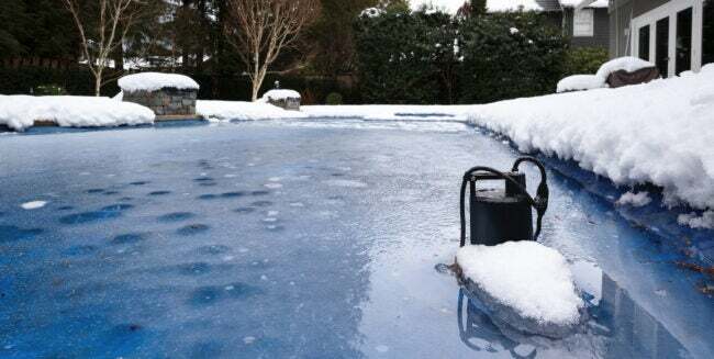 수영장 펌프는 얼어붙은 수영장 가장자리에 눈과 얼음으로 덮여 있습니다.