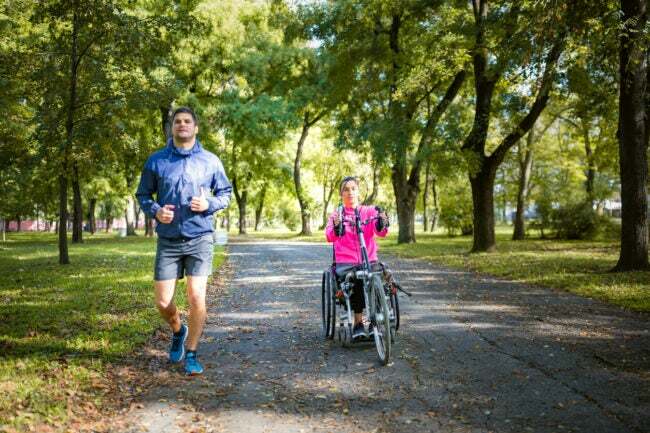 iStock-1286515623 ana planlı topluluk Tekerlekli sandalyeli kadın atlet erkek arkadaşıyla açık havada spor yapıyor