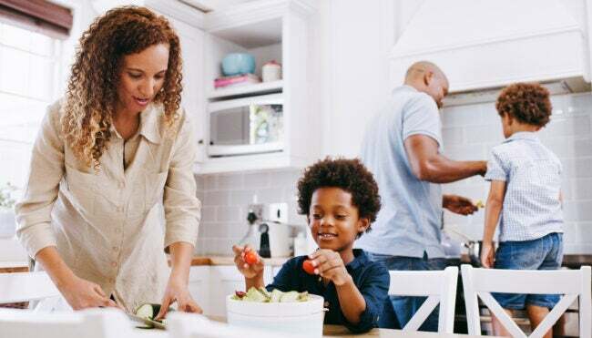 Vaření, kuchyně a černošští rodinní rodiče s dětmi připravují ingredience, zásoby nebo spotřební materiál na večeři, oběd nebo brunch. Ovocný salát, zdravé zdraví a máma na výživu pomáhají s přípravou jídla