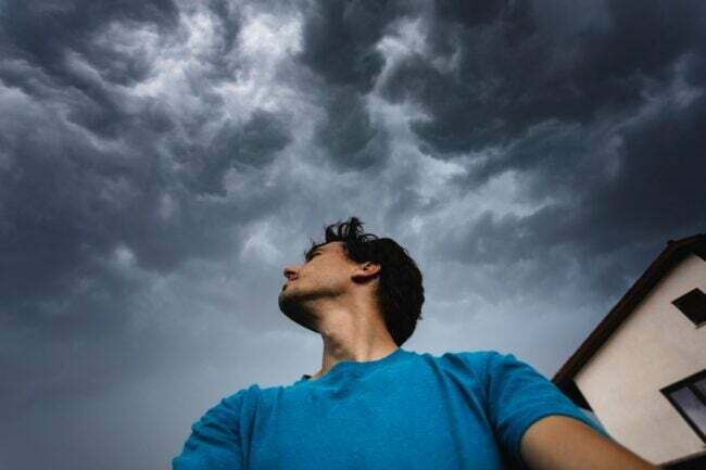 Hombre mirando hacia un cielo oscuro y nublado