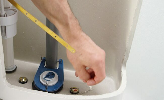 A mão de uma pessoa instalando um novo flapper de banheiro
