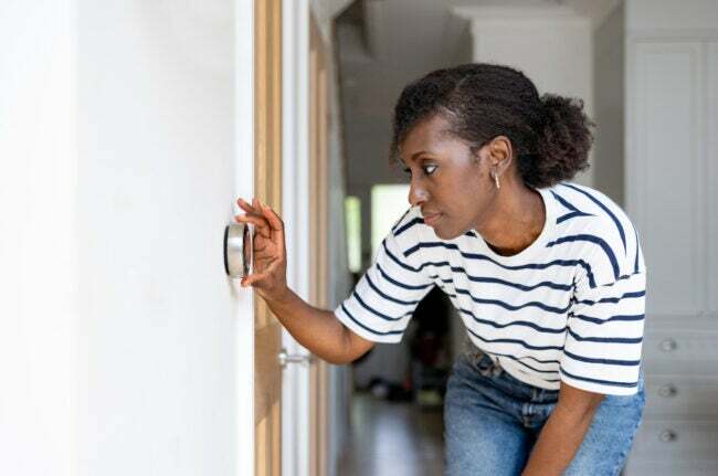 elektrisk ugn vs gas kvinna justera termostat i hemmet