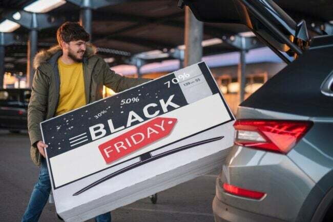 Mies laittaa Black Friday -laatikkoa autoon.