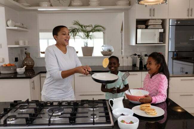 Vorderansicht einer afroamerikanischen Mutter und ihrer Kinder, die zu Hause auf einer Arbeitsplatte in der Küche Essen zubereiten
