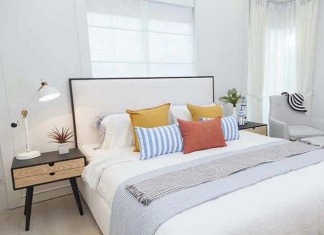 kamar tidur putih dengan tempat tidur rapi dan bantal warna-warni
