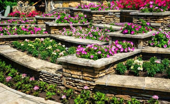 Konut arka bahçesinde istinat duvarları ve teraslı çiçek tarhları ile çevre düzenlemesi.