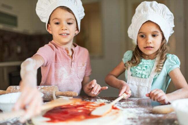 Mali dječak i djevojčica pripremaju hranu u kuhinji.