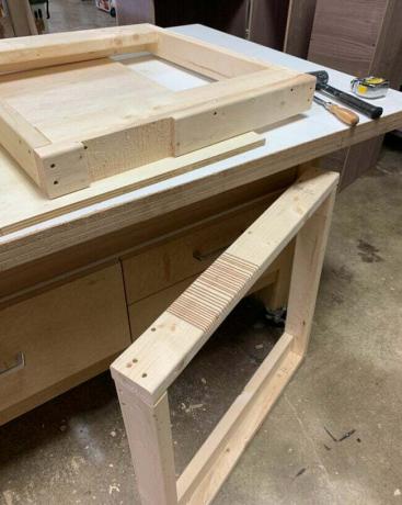 Dua bagian meja kerja di bengkel dengan palu dan pahat kayu.