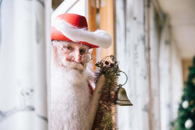 ซานต้าแอบมองผ่านประตูพร้อมหมวกสีแดงและระฆัง