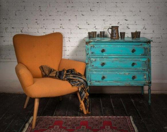 Poltrona vintage laranja, armário azul e cachecol ornamentado 