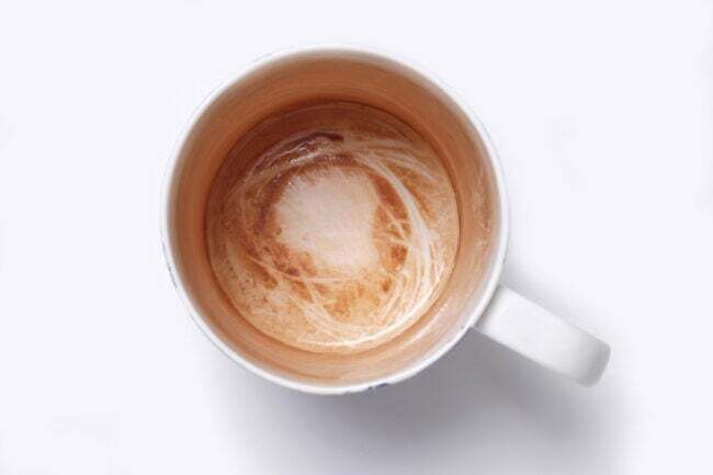 白い背景に対してコーヒーの汚れが付いたマグカップのオーバーヘッド ビュー