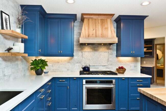 Küche-mit-blau gestrichenen-Schränken-und-einer-Holz-Dunstabzugshaube