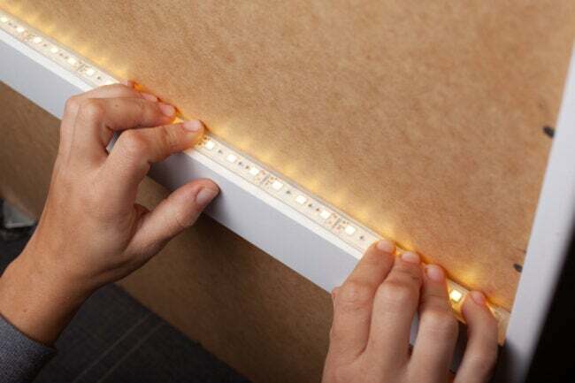 Mains installant des bandes lumineuses LED sur des meubles