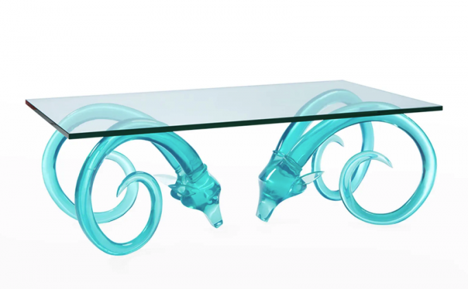 ガラスのトップとベースが、長く螺旋を描く繊細な角を持つ 2 つの青緑色の半透明の雄羊の頭で作られたカクテル テーブルの製品ショット
