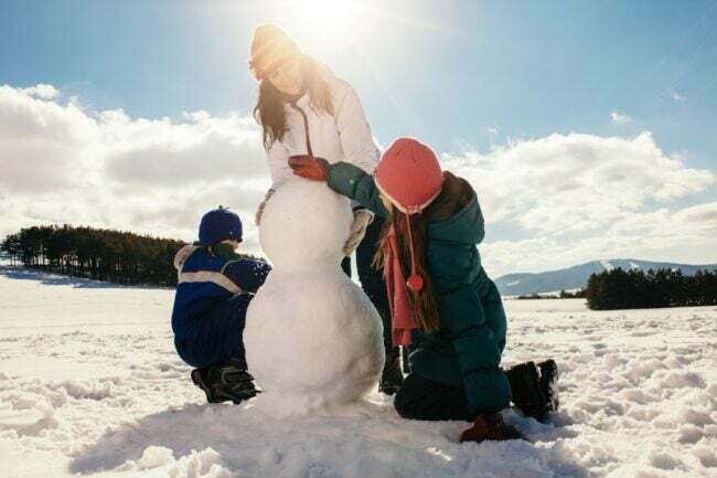 Malá rodinka, ktorá vonku vyrába malého snehuliaka