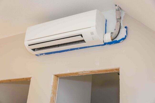 Mini-split kanaalloze airconditioning geïnstalleerd in onafgewerkte kamer met schilderstape eromheen