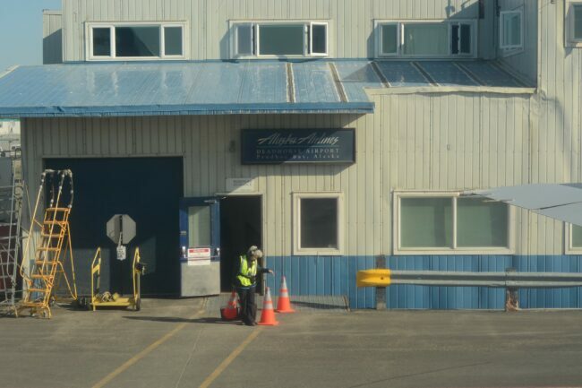 žena letisková pracovníčka stojaca pred letiskom Deadhorse na Aljaške