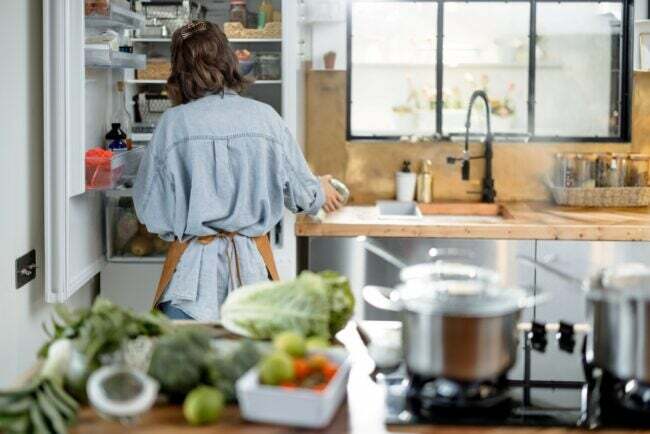 מטבח מלוכלך - אישה מסתכלת לתוך המקרר