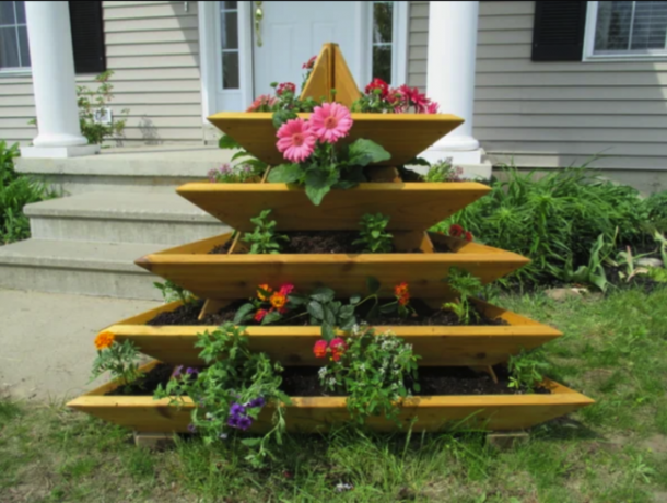 dřevěný patrový zahradní držák ve tvaru pyramidy s rostlinami v květináčích před dvorkem