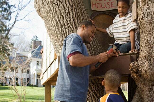 Pai e filhos construindo casa na árvore