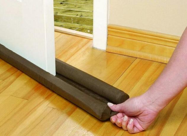Izolație cu spumă neagră glisând manual pe partea de jos a ușii.