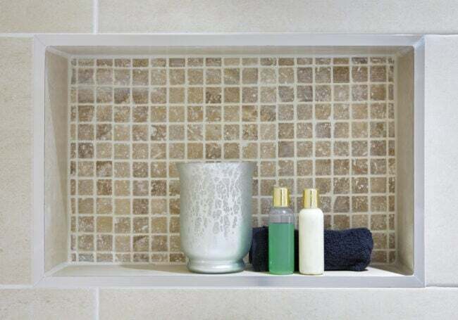 nicho de ducha con azulejos beige y botellitas de productos de baño