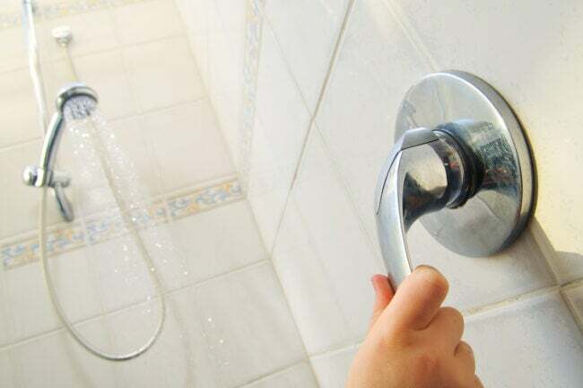 ranka įjungiant dušą pakeitus dušo vožtuvą