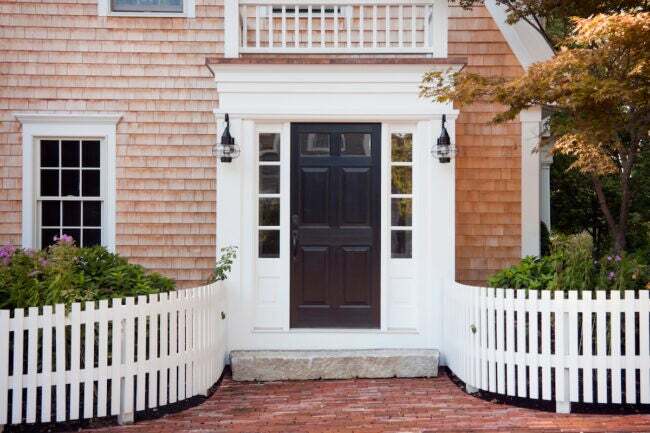 בית שייק ארז עם גדר כלונסאות לבנה מעוקלת המובילה לדלת הכניסה