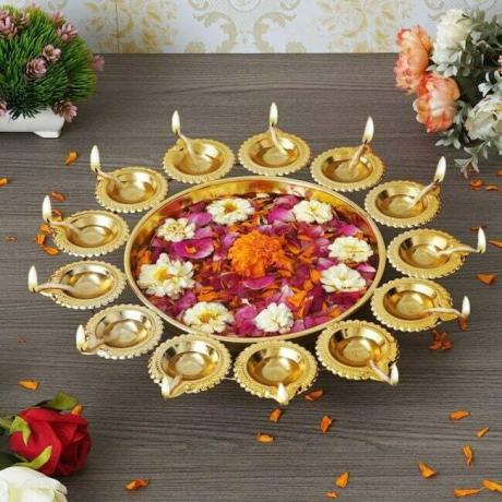 दिवाली उत्सव के लिए फूलों और दीयों के साथ सोने की सजावटी उर्ली कटोरी