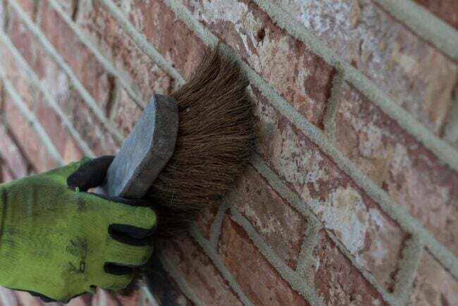 Usando pincel na parede de tijolos
