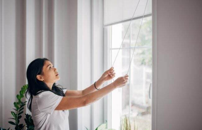 Mujer bajando las persianas durante el día