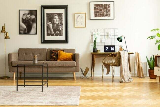 Nappali modern lakberendezéssel, beleértve a parkettás padlót, a galéria falát és egy barna kanapét