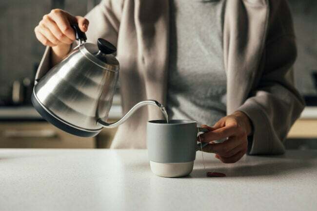 до невпізнання жінка наливає воду в чайну чашку