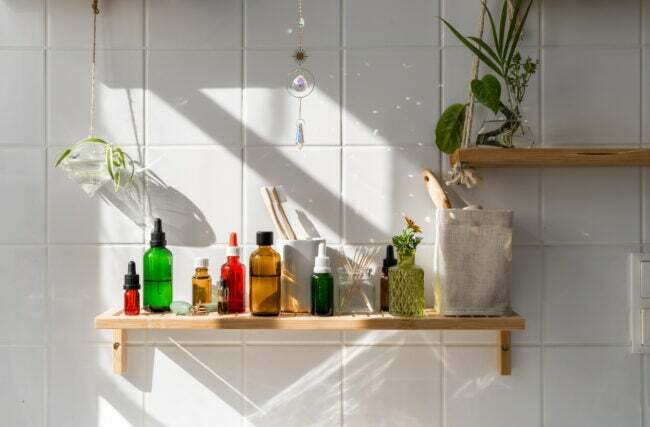 Banyodaki beyaz kiremitli duvardaki ahşap rafta çeşitli güzellik ürünleri.